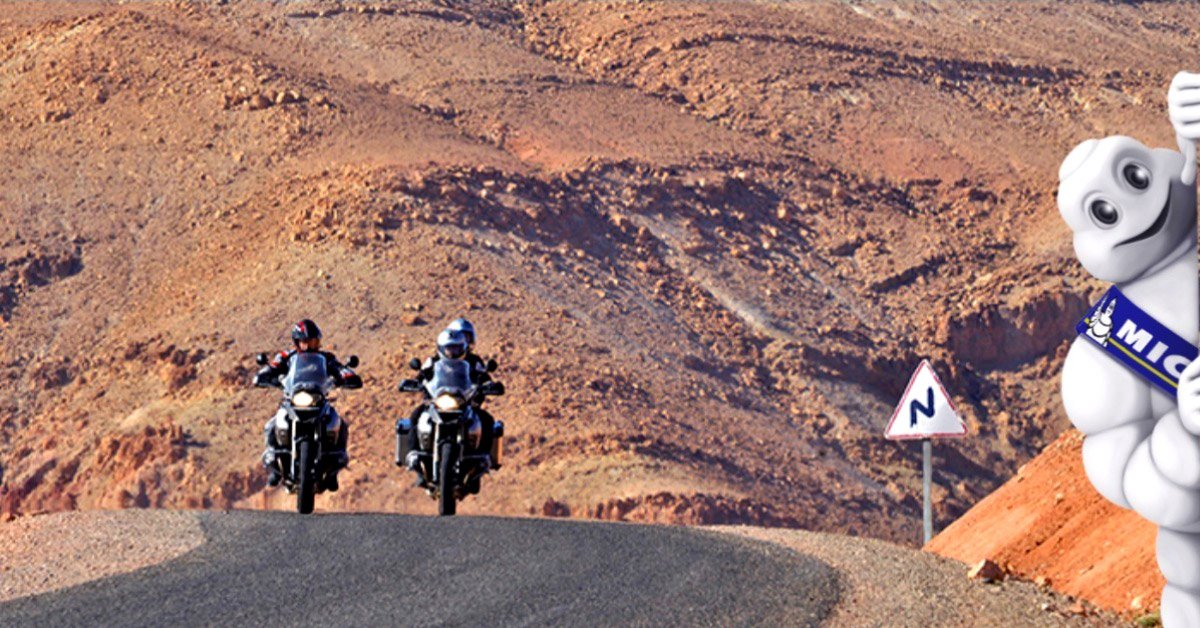aThree people riding two bikes in a tarmac deserted road aThree people riding two bikes in a tarmac deserted road